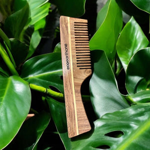 Sheesham wood comb among green leaves, showcasing a natural and eco-friendly hair care option.