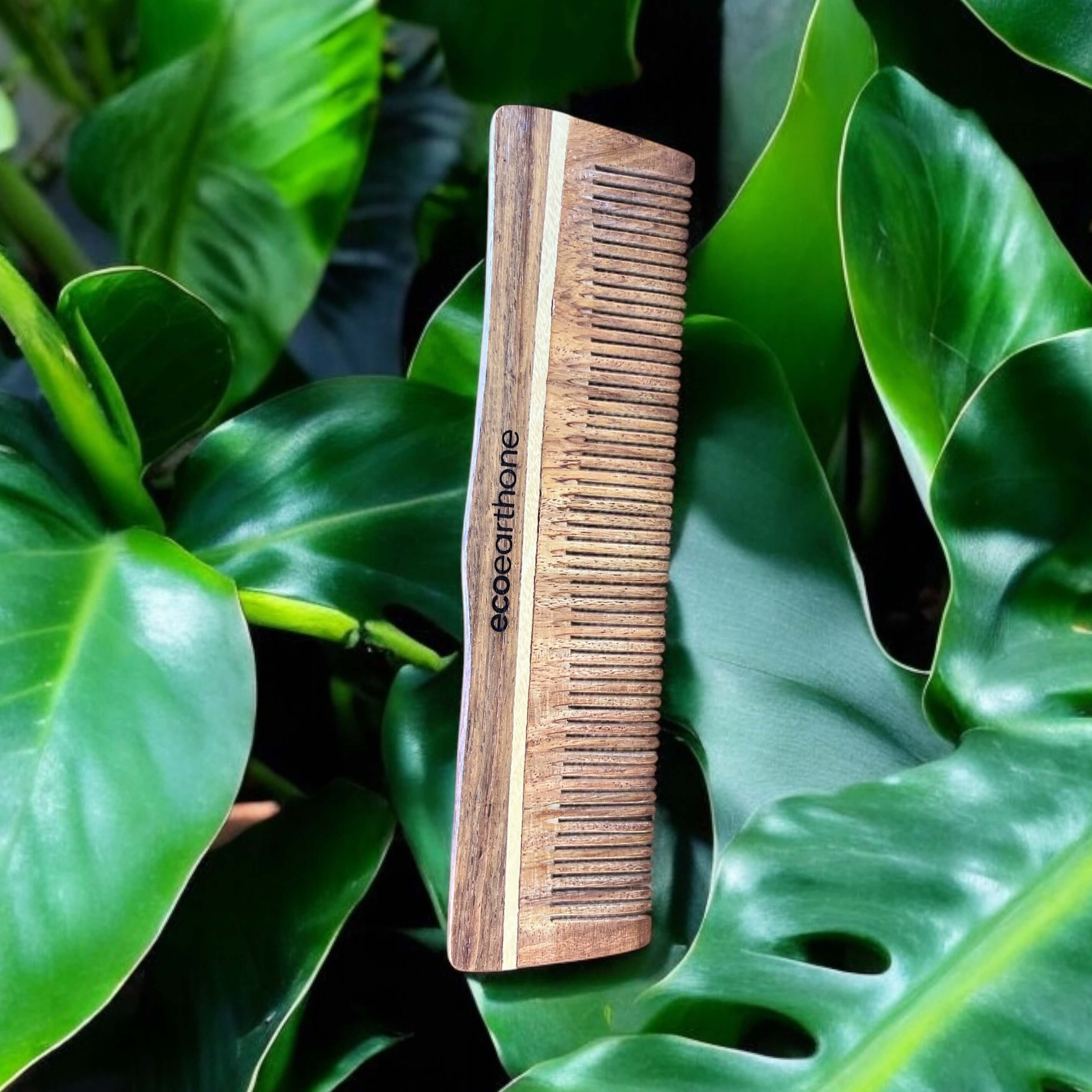 Sheesham wood comb surrounded by green leaves, showcasing eco-friendly design and premium natural materials.